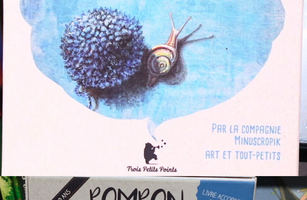 Recto et verso du coffret. Sur le recto un escargot et un pompon bleu sur une tache bleue derrière des explications sur le contenu du coffret : un livre accordéon, un CD et un code MP3