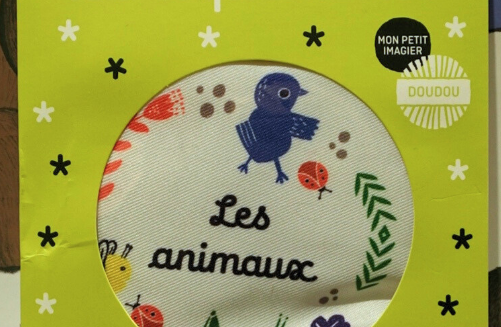 Un livre poussette en tissu emballé dans un carton vert pomme (avec une fenêtre transparente)