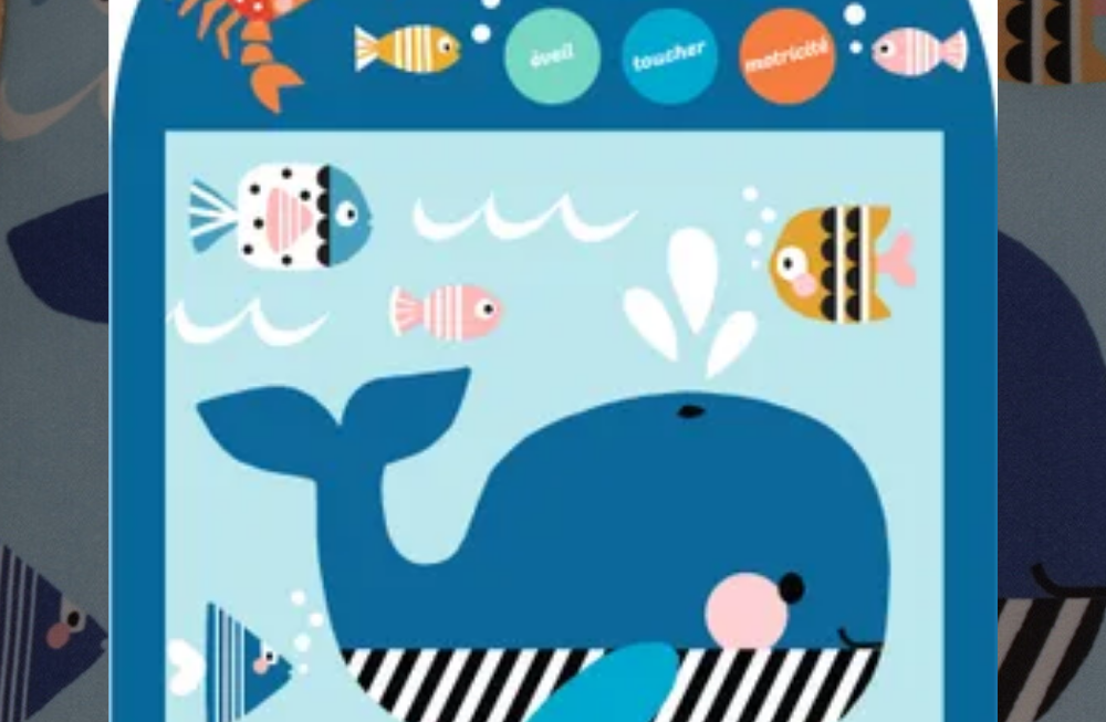 Une livre en tissu dans un emballage cartonnée : sont représentés une baleine, un crabe et des poissons