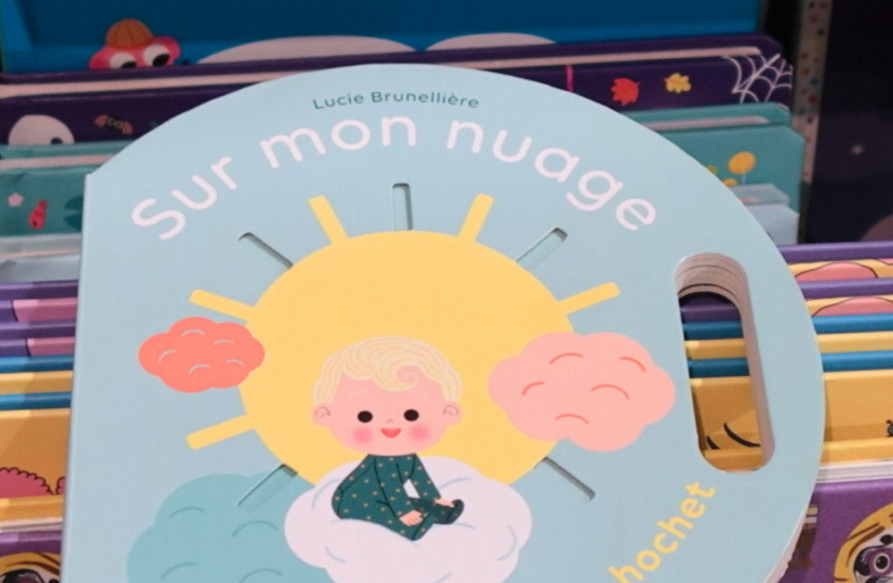 Livre rond avec un bébé et une poignet pour que l'enfant puisse le secouer comme un hochet; Il y a des découpes sur la couverture.